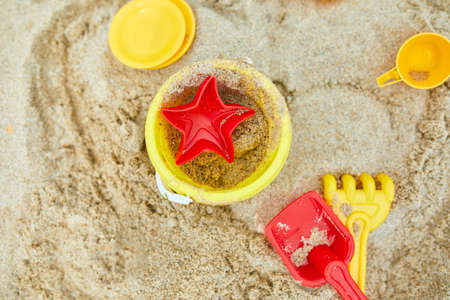 Top view, flat lay of  scattered plastic beach toys on sand background, family summer vacation,...