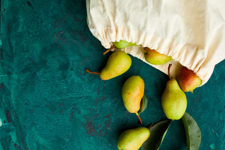 Fresh ripe fruits pears in string reusable shopping eco bag on a green background, grocery concept, Flat lay, Eco friendly, autumn harvest. Copy space.の写真素材