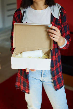Brunette woman opening, hold in hand online order parcel box with cosmetics at home, Female customer...