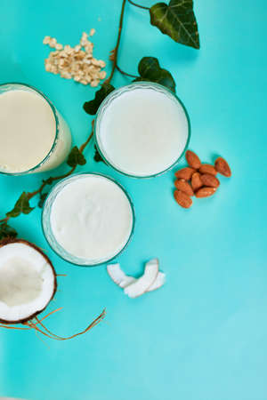 Various vegan plant based milk and ingredients, non-dairy milk, alternative types of vegan milks in glasses on a blue background , flat lay, top view with copy spaceの写真素材