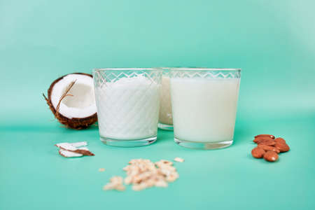 Various vegan plant based milk and ingredients, non-dairy milk, alternative types of vegan milks in glasses on a blue background with copy spaceの写真素材