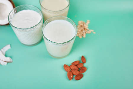 Various vegan plant based milk and ingredients, non-dairy milk, alternative types of vegan milks in glasses on a blue background with copy spaceの写真素材