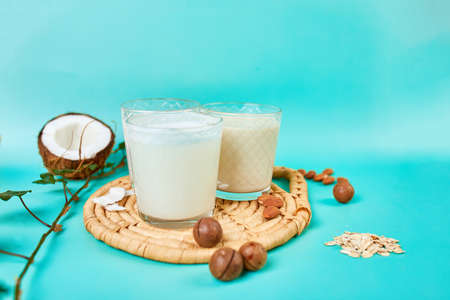 Various vegan plant based milk and ingredients, non-dairy milk, alternative types of vegan milks in glasses on a blue background with copy spaceの写真素材