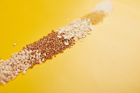 Flat lay of set of heap various grains and cereals bulgur, rice, oatmeal, buckwheat, couscous wheat seeds on yellow background, copy space, space for text, top view.の写真素材
