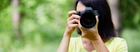 Banner of Portrait of a woman photographer covering her face with the camera outdoor take photo, World photographer day, Young woman with a camera in hand.の写真素材