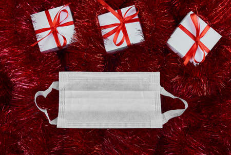 Christmas white gifts box on red tinsel background and protective maskの写真素材