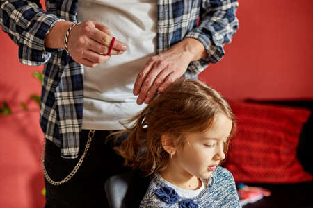 Father combing, brushing his daughter's hair at home, father and daughter smiling, family moments, spending time together.の写真素材
