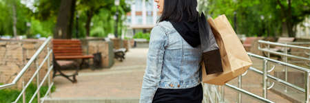 Banner of Woman holding several paper bags with purchased things walking outdoors in the park, girl...
