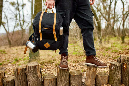 Tourist man hold in hand  backpack, Travel concept, Autumn background landscape, travel accessory,...
