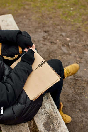Travel woman with red hat in black jacket write on notebook, make notes, drawing some sketche...