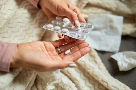 Top view Sick woman putting medicine in hand and take it, while recovering at home, ill woman taking...