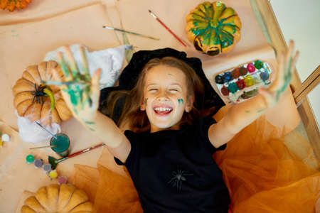 Top view of Smiling girl lying on the floor between drew pumpkin Halloween, and decoration for party, paint hands, emotion, make faces.の写真素材