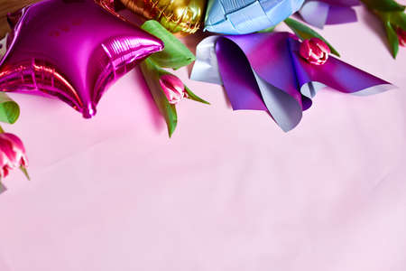 Flat lay style of color balloons with tulips floral decoration on pink background. Birthday, holiday or party concept, copy space for text.の写真素材