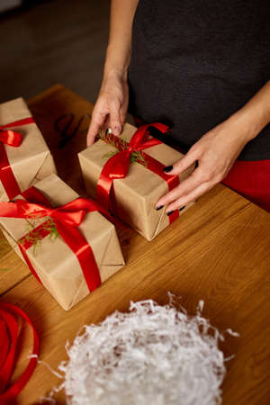 Hands of cropped unrecognisable woman packing Christmas present, Eco friendly packaging kraft paper gifts, Female wrapping a Christmas present, gift boxの写真素材