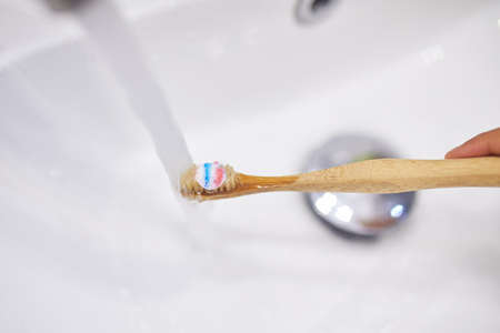 Ecologe wooden Toothbrush with toothpaste under water jet at home, healthy hygiene conceptの写真素材