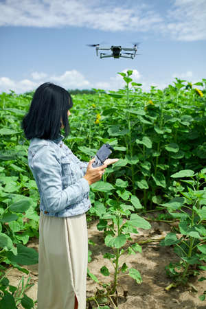 Young woman learning how to pilot her drone in,  female using, piloting, fly drone on field of...