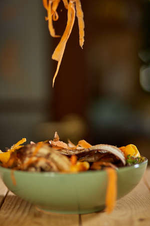 Women scraps peels carrots vegetable peeling, throws in compost bucket, organic compostingの写真素材