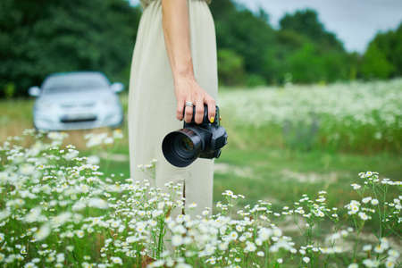 Unrecognizable woman hold digital camera in her hands on flower field landscapeの写真素材