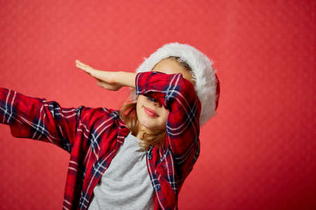 Christmas little Girl in Santa Hat, smiling and dancing, happy child on isolated red studio background, Merry Christmasの写真素材