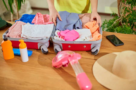 Unrecognizable Woman hand packing suitcase, put snorkeling, diving mask, getting ready for summer...