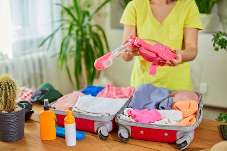 Woman hand packing suitcase, put snorkeling, diving mask, getting ready for summer vacation trip...