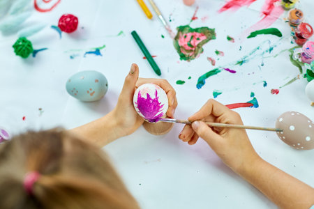 Unrecognizable little girl painting, drawing with brush eggs at home. Child preparing for Easter, having fun and celebrating feast. Happy Easter, DIYの写真素材