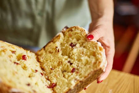 Woman hand cut Easter cake on wooden rustic table. The concept of preparing for the Easter holiday.
