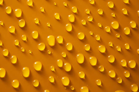 Abstract water drops on orange bronze background, macro, Bubbles close up, Cosmetic moisturizing liquid drops, Flat lay pattern.の写真素材