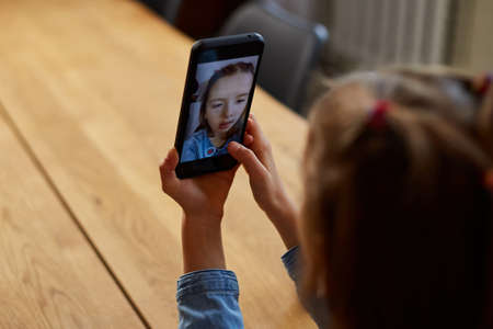 Beautiful young girl filming her blog broadcast about healthy food at the home. Little girl choosing between sweet cake and fresh red apple in , Healthy dieting habit, concept of proper nutritionの写真素材
