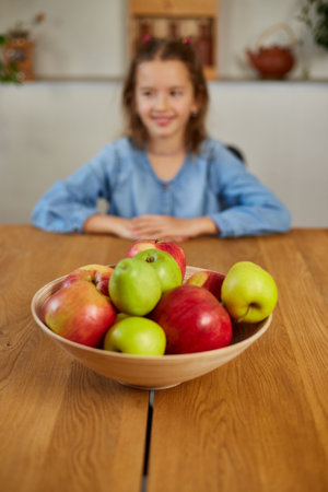 Little happy girl hold bowl with fruits in the kitchen at home, healthy child snack, Healthy food at home, love fruit and vitamins.の写真素材