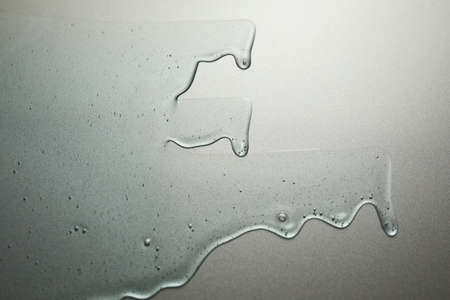 Blue cream liquid gel serum flows down on silver texture, makeup and cosmetics background, skincare...
