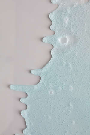Blue cream liquid gel serum flows down on silver texture, makeup and cosmetics background, skincare or hair productの写真素材