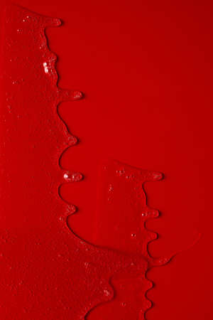 Cream liquid gel serum flows down red silver texture, makeup and cosmetics background, skincare or hair productの写真素材