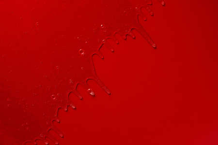 Cream liquid gel serum flows down red silver texture, makeup and cosmetics background, skincare or hair productの写真素材