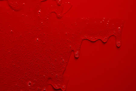 Cream liquid gel serum flows down red silver texture, makeup and cosmetics background, skincare or hair productの写真素材