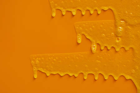 Cream liquid gel serum flows down on yellow texture, makeup and cosmetics background, skincare or hair productの写真素材