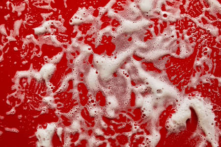Texture of white soap foam with bubbles abstract red background, Soap, shower gel, shampoo, Face Cream cleansing mousse sample.の写真素材