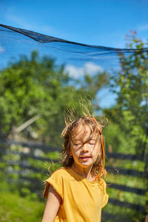 Portrait of young girl on her trampoline outdoors, in the backyard of the house on a sunny summer day, summertime vacation, Happy little child jumping on trampolineの写真素材