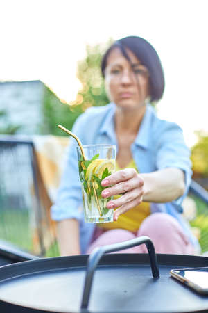 Woman take summer citrus lemonade with reusable metal straws party in a backyard house with cold drink, summertime, eco friendly drinking straw, Healthy lifestyle, vegetarian food, detox waterの写真素材