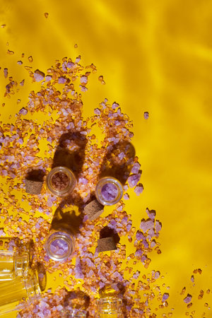 Flat lay bottle sea salt with natural spa products cosmetic, product mockup with water wave,, clean aqua splashing on yellow background sunlight, summerの写真素材