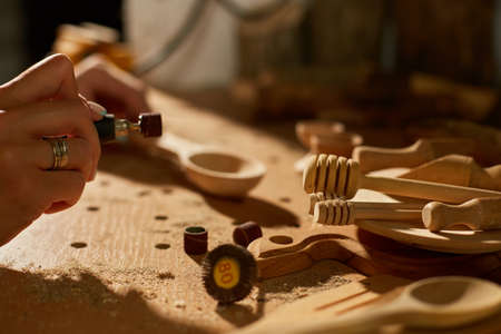 Female using power working tools graver for wooden utensils spoonの写真素材