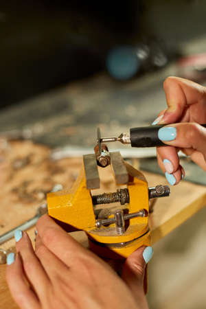 Woman using power working grinder machine, female hand grinds a metal nutsの写真素材