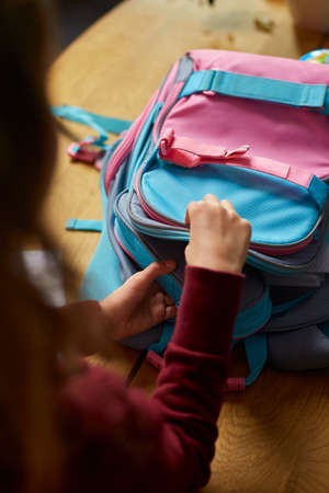 Schoolgirl put books and notes into backpack at home, pupil prepare staff for education, School supplies, Back to school concept.の写真素材