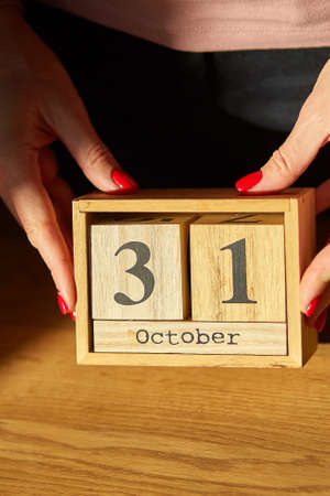 Woman hand change, sets the date on the wooden calendar on 31 Octoberの写真素材