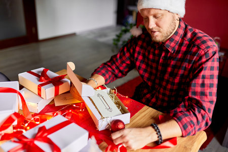 DIY, Man in Santa hat making greeting card for New Year and Christmas for friends or family , packing presents or gifts, mail manager concept.の写真素材