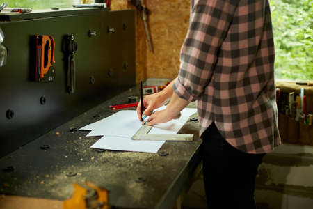 Female interior designer working on drawings, woman architect draws with ruler plan of new apartment design at workshop, design project blueprints for new construction projectの写真素材