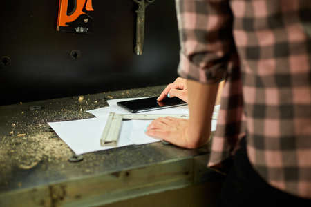 Female business owner using digital tablet in workshop, industrial woman engineer working with blueprints and tablet in the workshop.の写真素材