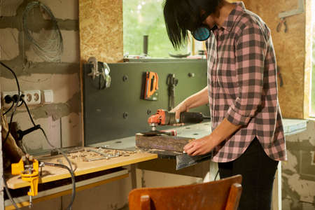 Close up of a worker woman hand grinds, sanding the wood in workshop, restoring antique