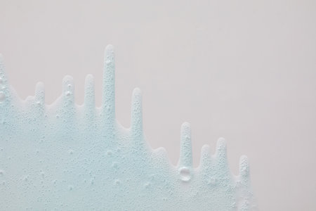 Blue cream liquid gel serum flows down on silver texture, makeup and cosmetics background, skincare or hair productの写真素材