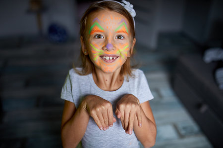Child with painted face on halloween, having fun, leisure together at home on the sofa, dark light,...
